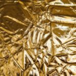 High-resolution image of crumpled gold fabric, perfect for backgrounds and designs.